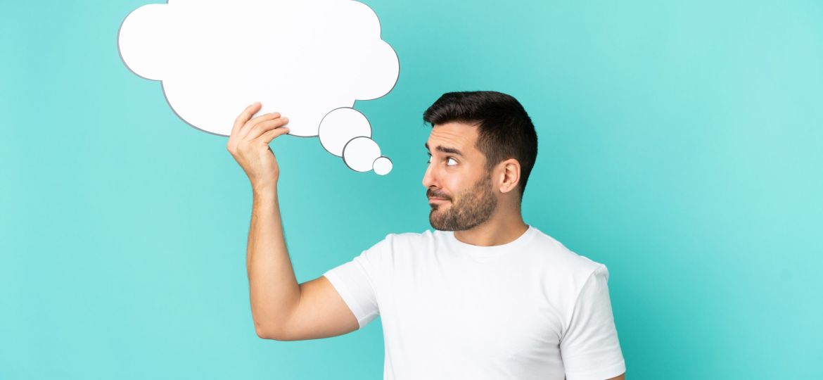 Young handsome caucasian man isolated on blue background holding a thinking speech bubble